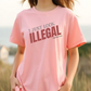 Woman wearing a pink t-shirt with 'I Just Look Illegal' text outdoors.